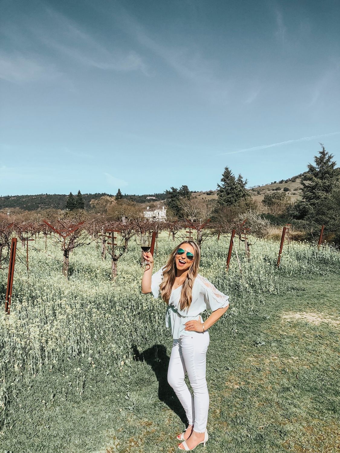 A visitor with a glass of red wine among the vines
